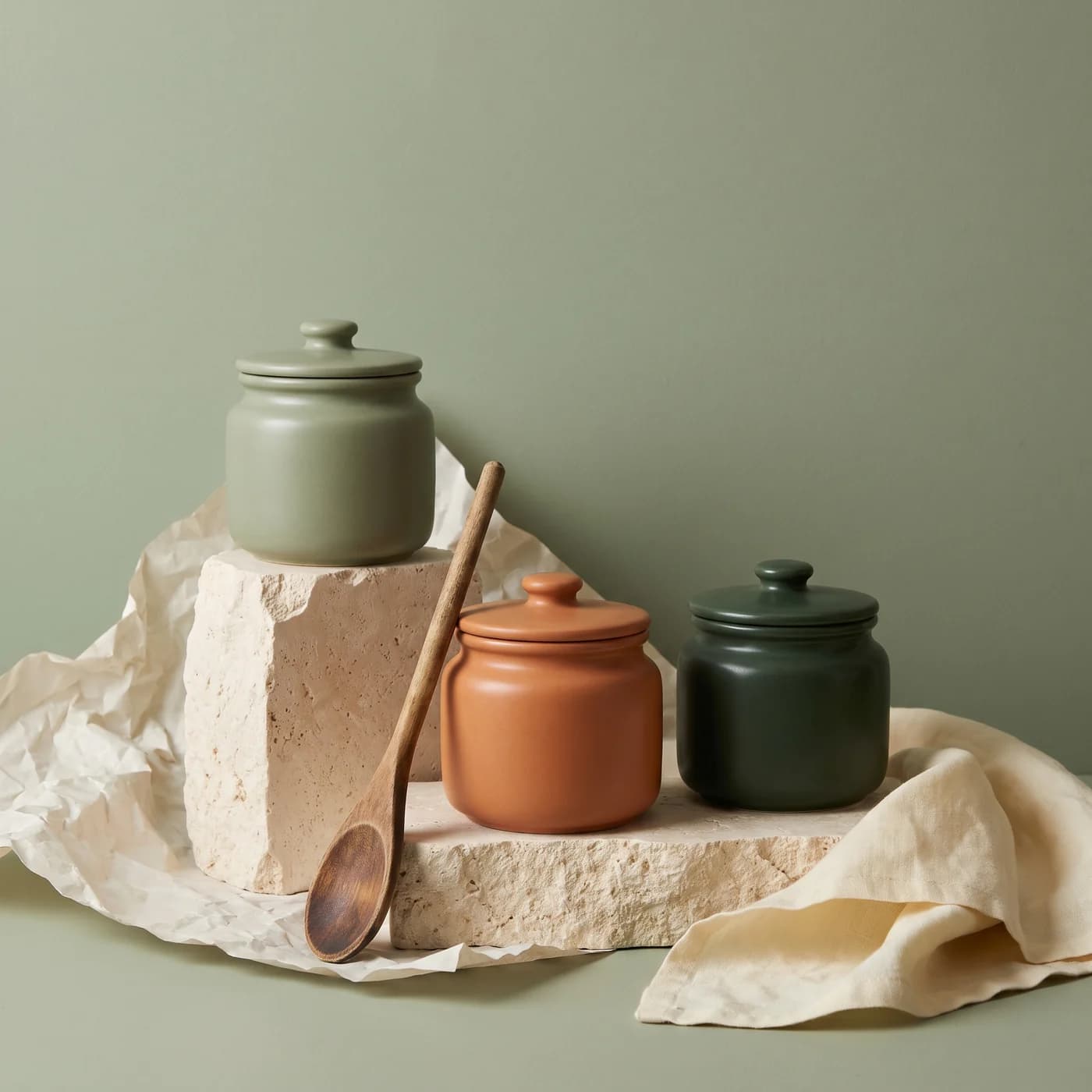 Three lidded ceramic storage pots on pale plinths