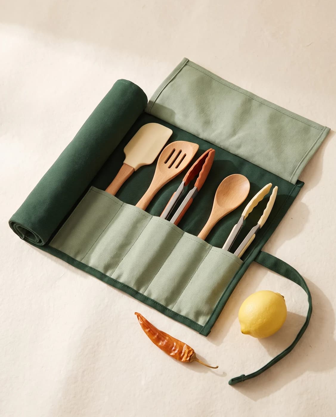 A green canvas utensil wrap opened to show kitchen tools