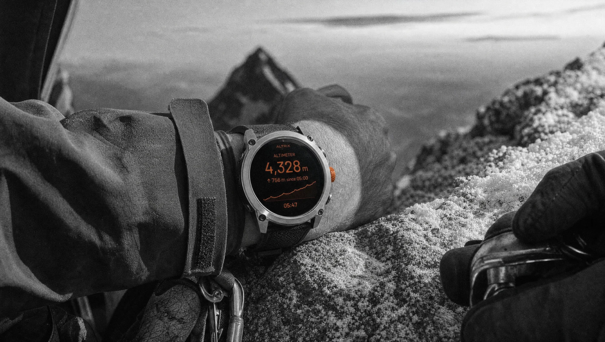 A climber's wrist on a summit ridge at first light, the whole frame monochrome except the ALTRIX altimeter face reading 4,328 metres and the ember crown beside it.