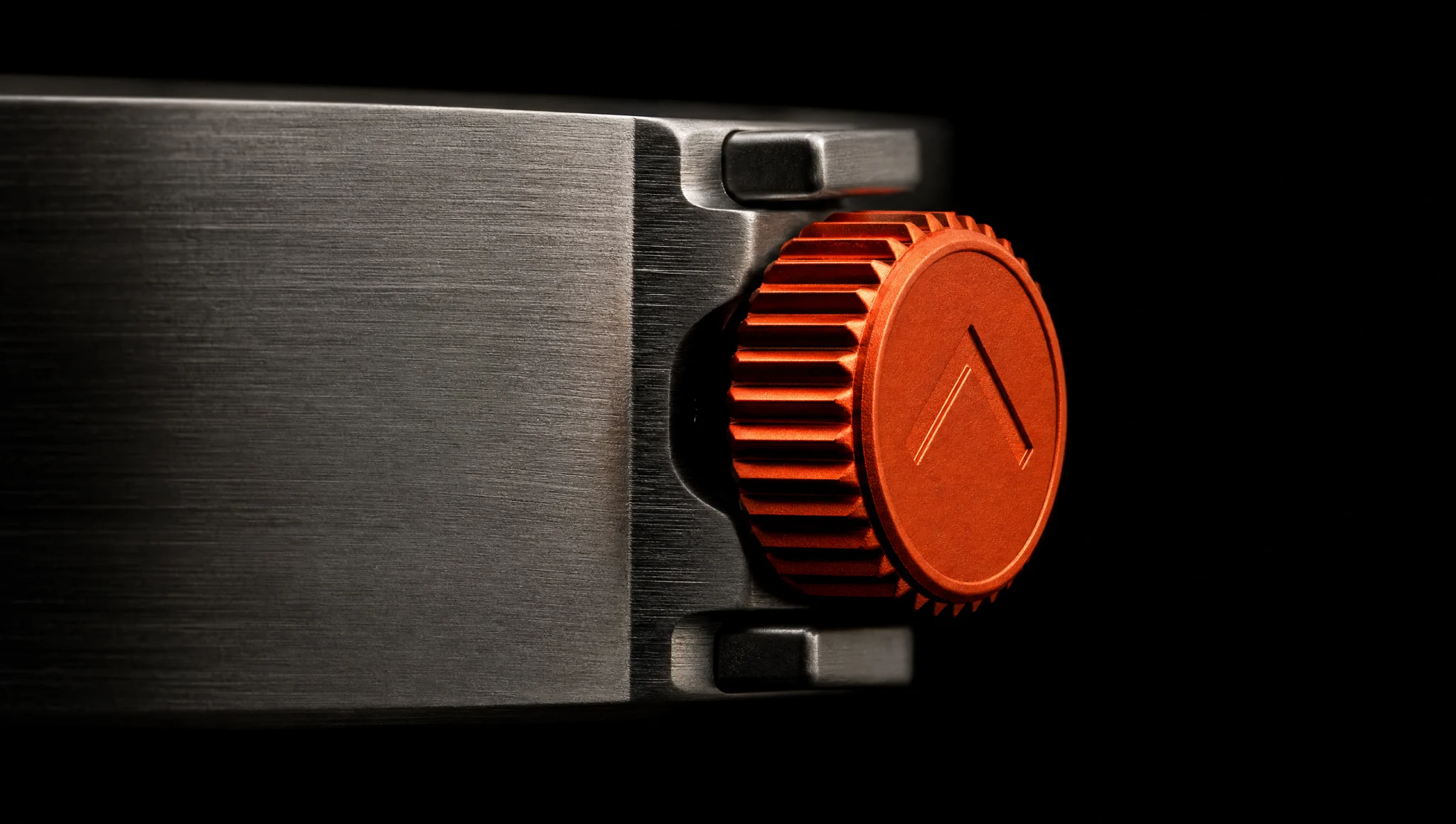 Macro of the ember knurled crown seated in the brushed titanium case flank.